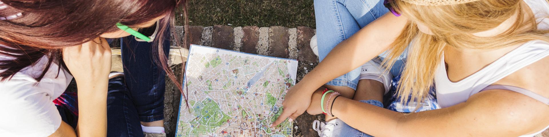 High Angle View Of Two Female Hikers Looking For Direction In Map