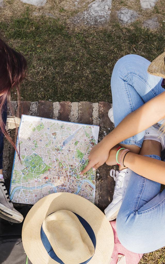 High Angle View Of Two Female Hikers Looking For Direction In Map