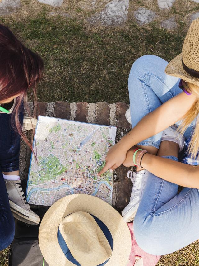 High Angle View Of Two Female Hikers Looking For Direction In Map